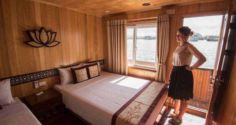 Vrouw staand in een gezellige houten lambrisering hut met een groot raam uitkijkend op de haven