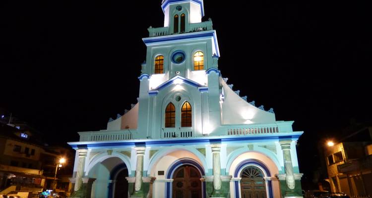 Vue nocturne d'une façade d'église éclairée en turquoise contre un ciel sombre