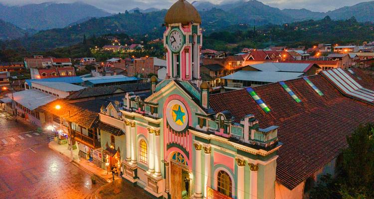 Tour d'horloge colorée et église au crépuscule surplombant une petite ville andine