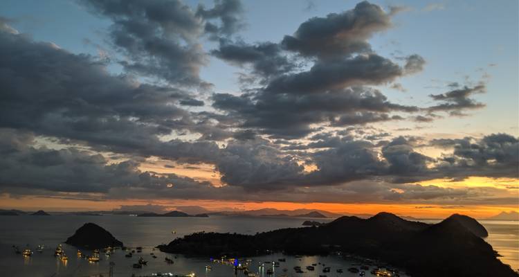 Les nuages dramatiques du coucher de soleil brillent au-dessus du port de Labuan Bajo parsemé d'îles.
