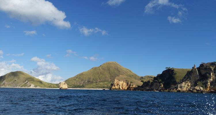 Des collines rocheuses et verdoyantes s'élèvent des mers d'un bleu profond lors d'une journée ensoleillée à Komodo.