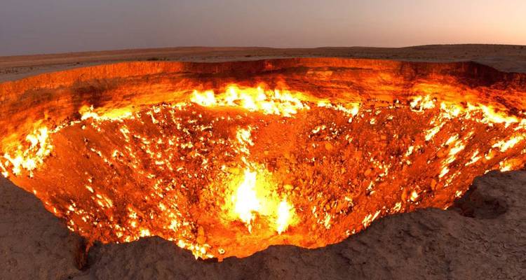 Cratère gazier ardent de Darvaza brillant intensément dans le désert au crépuscule.
