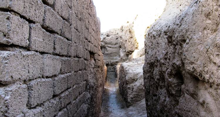 Passage étroit entre d'anciens murs de briques de terre dans une ruine du désert.