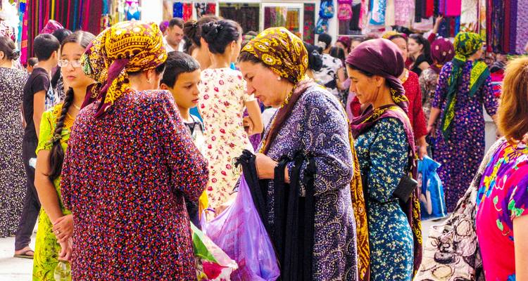 Bazar extérieur bondé avec des femmes en robes colorées à motifs examinant des marchandises.