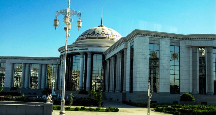 Impressionnant bâtiment universitaire à dôme avec façade ornementée contre un ciel bleu éclatant.