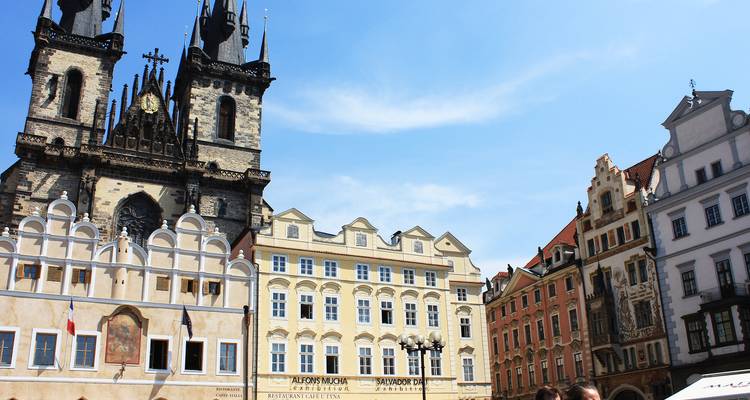 La Iglesia Gótica de Nuestra Señora ante Týn domina las coloridas fachadas en la Plaza de la Ciudad Vieja de Praga bajo un cielo despejado.