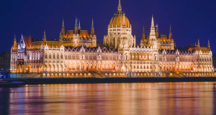 El Parlamento Húngaro está espectacularmente iluminado y se refleja en el Danubio por la noche.