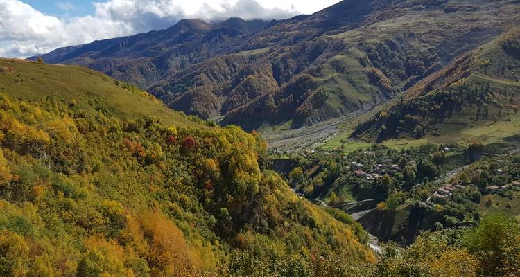 Colorful autumn foliage covering steep valleys and distant peaks in the Georgian highlands.