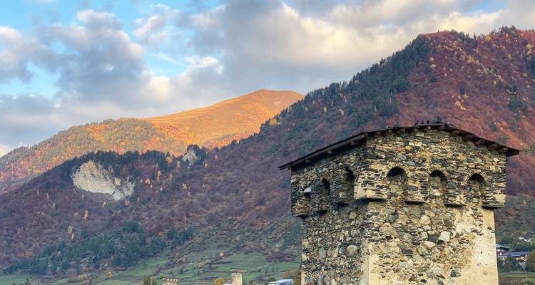 Stone Svan tower standing before a backdrop of colorful autumn mountainside under soft evening light.