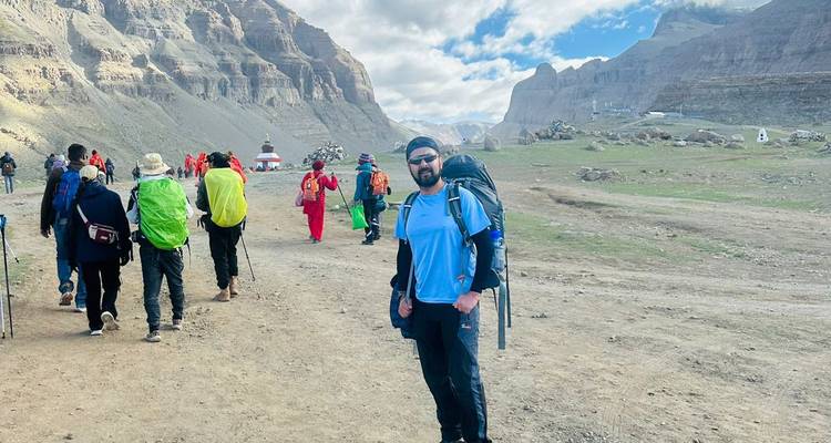 Trekking group walking through a high-altitude valley with rugged mountains and scattered clouds