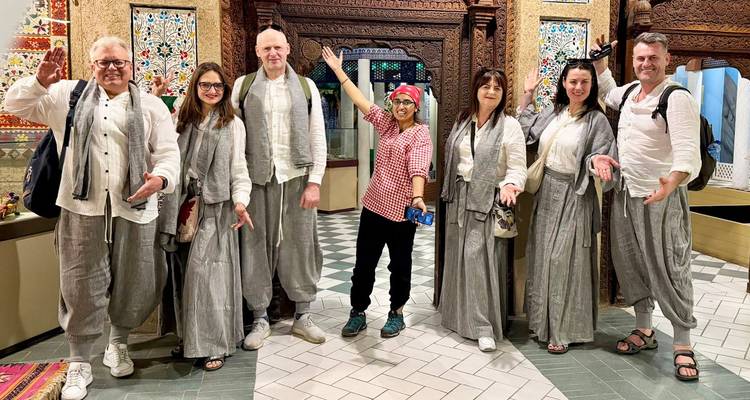 Des visiteurs portant des tenues traditionnelles prennent la pose dans une salle de musée richement décorée au Pakistan.