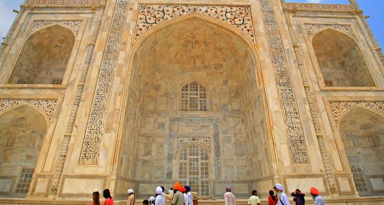 Visitors look up at the ornate marble entrance facade of the Taj Mahal