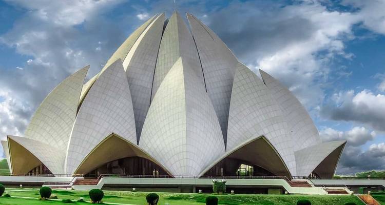 The modern white Lotus Temple contrasts with dramatic clouds