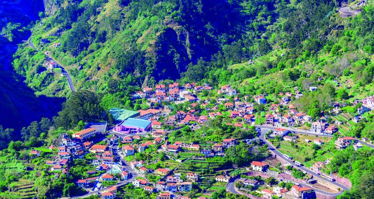 Vallée de montagne verdoyante parsemée de maisons aux toits rouges et de routes sinueuses de Curral das Freiras, Madère.