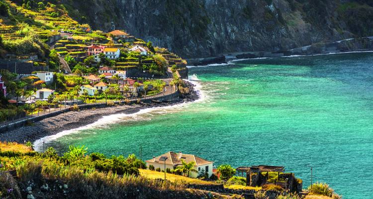 Charmantes Küstendorf mit terrassenförmigen Feldern überblickt funkelnde türkisfarbene Bucht