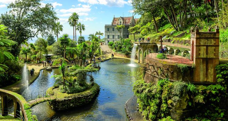 Üppiger Monte Palace Tropischer Garten mit Teichen, Springbrunnen und Besuchern, die auf den Wegen spazieren