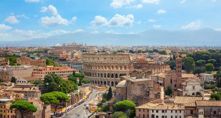 Panorama-Luftaufnahme von Rom mit dem Kolosseum inmitten der weitläufigen Stadtlandschaft und Bergen