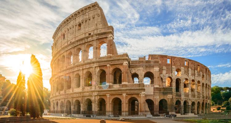 Sonnenstrahlen erhellen das antike Kolosseum vor einem streifigen Himmel