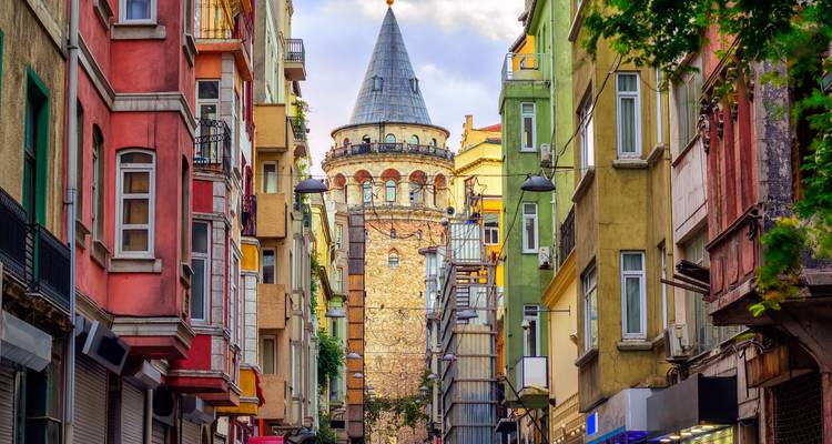 Lebendige schmale Straße rahmt den historischen Galata-Turm im sanften Abendlicht ein