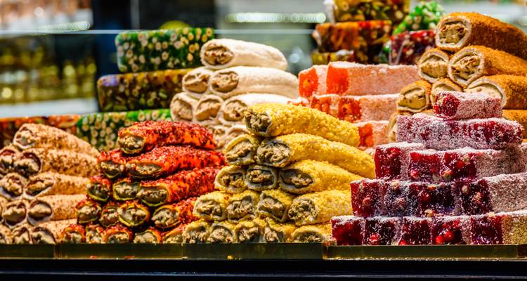 Lebhafte Stapel von verschiedenen türkischen Honig-Süßigkeiten, die hinter einer Glastheke in einem Süßwarengeschäft ausgestellt sind.