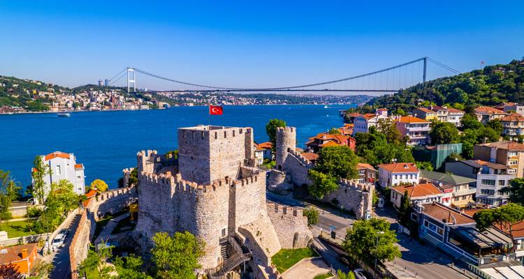 Luftaufnahme der Rumeli-Festung am Bosphorus mit der Bosporus-Brücke und der Istanbuler Skyline jenseits einer tiefblauen Meerenge.