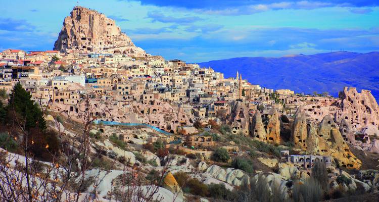 Panorama von Uchisars Felsenburg und den umliegenden Höhlenhäusern in Kappadokien unter einem strahlend blauen Himmel.