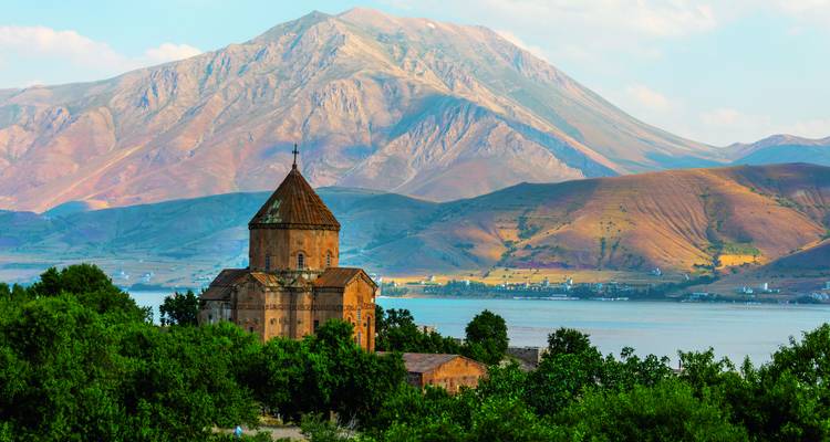 Historische armenische Kirche auf der Insel Akdamar vor dem Vansee und zerklüfteten Bergen im sanften Nachmittagslicht.