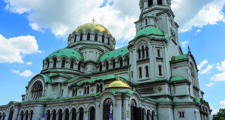 Große Kathedrale mit grünen Kuppeln und kunstvoll verzierter Architektur unter einem teilweise bewölkten Himmel