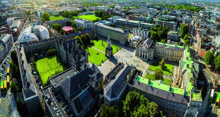 Luftpanorama des Trinity College und der Dubliner Innenstadt in hellem Sonnenschein mit grünen Rasenflächen und historischen Gebäuden.