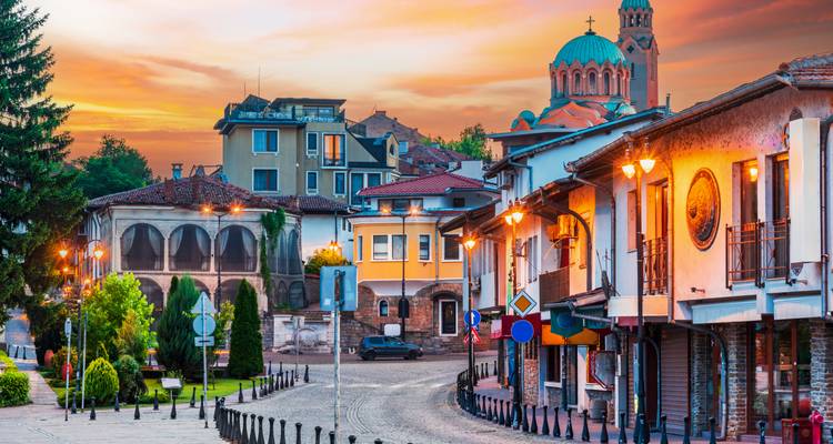 Bezaubernder Abendblick auf Veliko Tarnovos farbenfrohe Altstadt und Kuppelkirche unter warmem Himmel.
