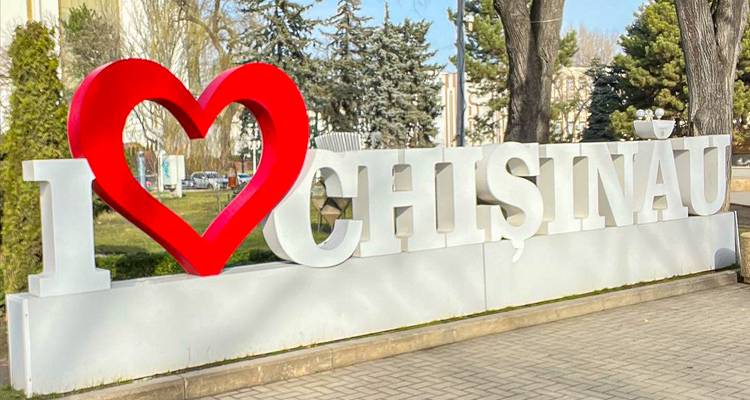 Groot sculpturaal bord met de tekst I ❤️ Chișinău langs een verharde wandelpad met bomen op de achtergrond.
