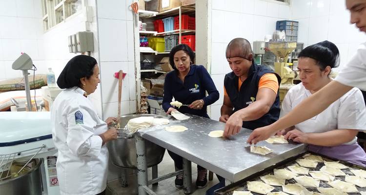 Kleine Gruppe von Bäckern, die Teig in einer Großküche formen.