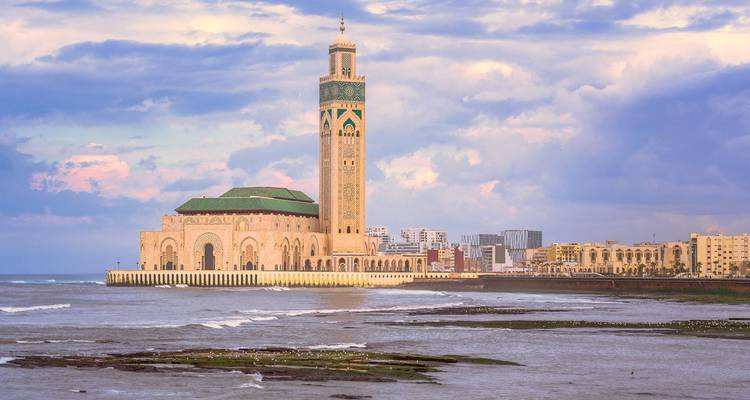 Iconische Hassan II-moskee verrijzend vanaf de Atlantische kustlijn met pastelkleurige wolken erboven
