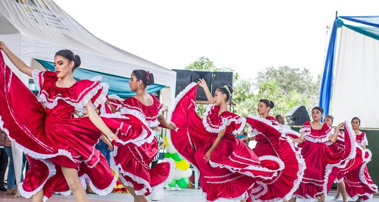 Des danseurs traditionnels font tournoyer des robes rouge vif lors d'une performance culturelle animée en Équateur.