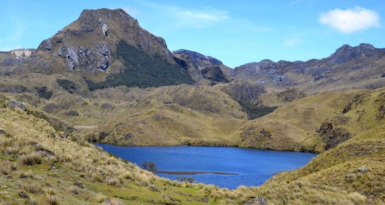Un lac alpin bleu serein se niche parmi les collines dorées ondulantes du páramo dans le parc national de Cajas.