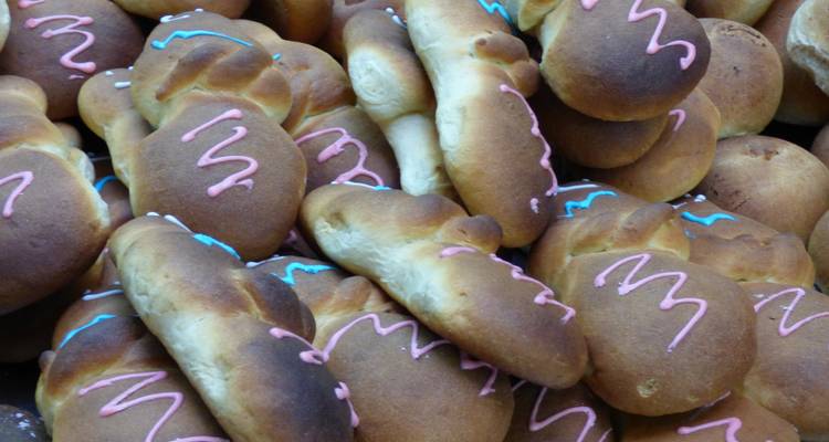 Des pains sucrés équatoriens traditionnels décorés de glaçage coloré sont empilés dans une vitrine de boulangerie.