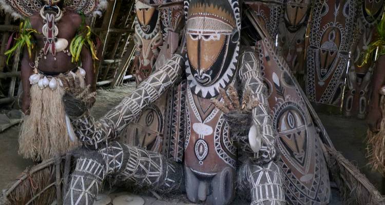 Close-up van grote gebeeldhouwde voorouderfiguur versierd met geometrische klei- en okerpatronen.