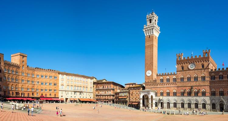 Large place avec le Palazzo Pubblico en briques rouges et la Torre del Mangia qui s'élance sous un ciel bleu clair