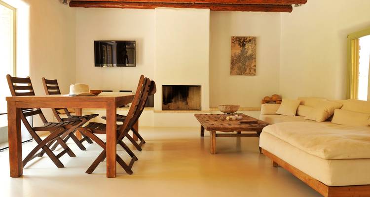 Salon et salle à manger minimalistes lumineux avec mobilier en bois, cheminée et canapé crème.