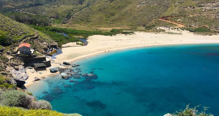 Vue panoramique de la baie turquoise avec une petite chapelle sur un promontoire rocheux et une plage de sable en contrebas des falaises