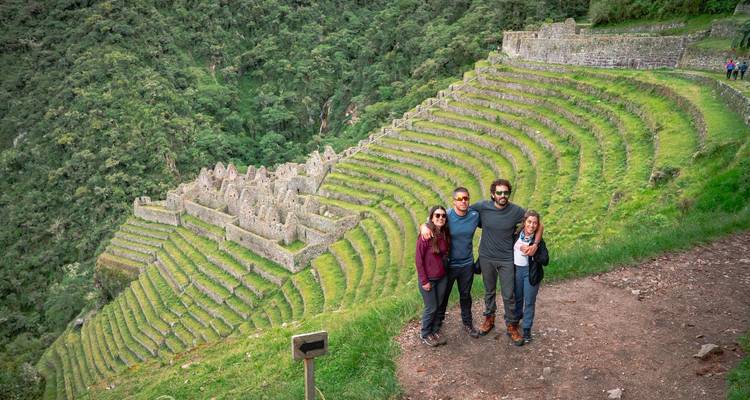 Four friends pose above the lush circular terraces and ruins of Winay Wayna in the cloud forest.