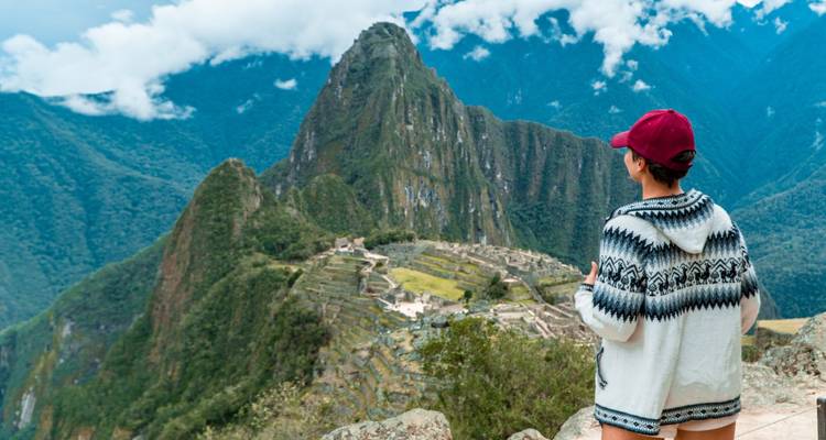 A traveler gazes at the iconic citadel of Machu Picchu perched among misty emerald peaks.
