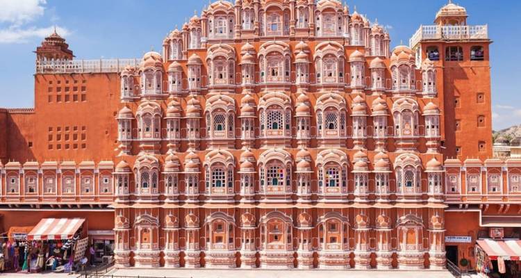 Symmetrical pink sandstone facade of Hawa Mahal with vibrant blue sky above.