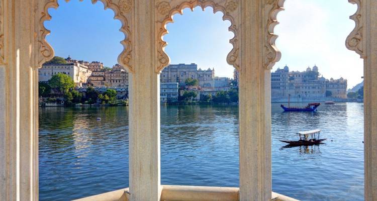Lake Pichola and the Udaipur cityscape framed by ornate scalloped marble arches.