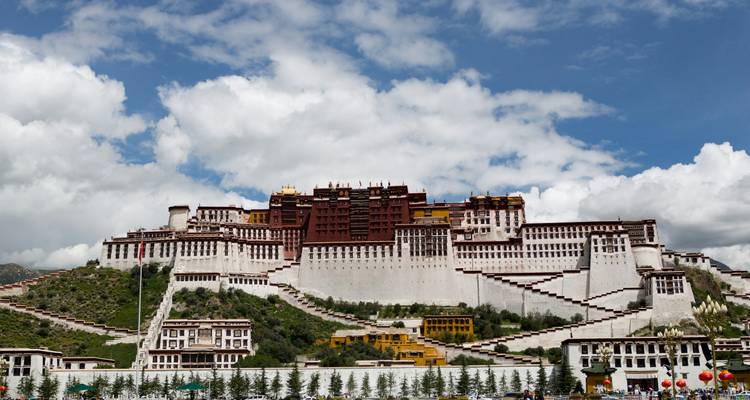 Grote Potala Paleis dat uittorent boven Lhasa onder een heldere blauwe hemel met verspreide wolken.