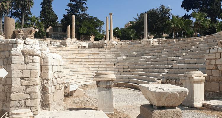 Asientos de piedra del antiguo anfiteatro romano rodeados por pilares y ruinas esparcidas.