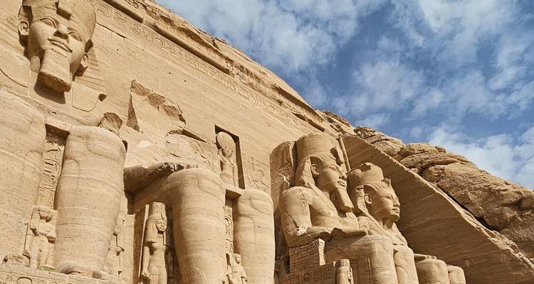 Vista en primer plano desde abajo de las colosales estatuas sentadas en Abu Simbel talladas en acantilados de arenisca.