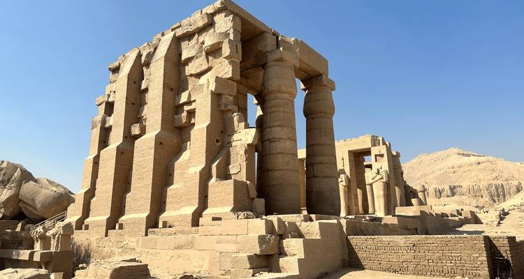 Ruinas de arenisca iluminadas por el sol de un complejo de templos antiguos que se alzan contra un cielo azul brillante del desierto cerca de Luxor.