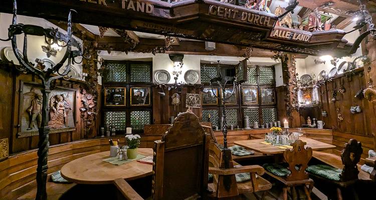 Gezellig houten Duits kroeginterieur met lambrisering, gesneden meubilair, kaarsen en traditionele decoratie.