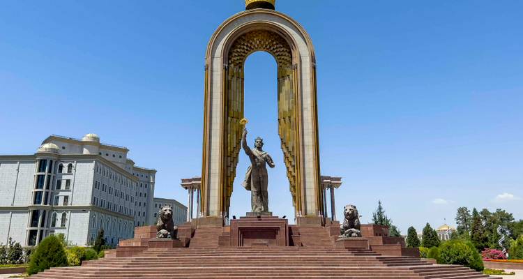 Monument présentant une figure en bronze sous une arche dorée flanquée de statues de lions par une journée ensoleillée.
